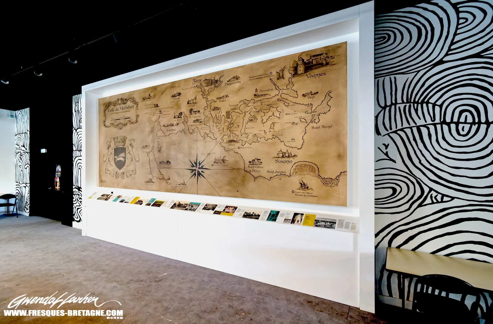 Grande carte peinte du Golfe du Morbihan dans une salle d'exposition, encadrée de murs à motifs d'art pariétal noir et blanc